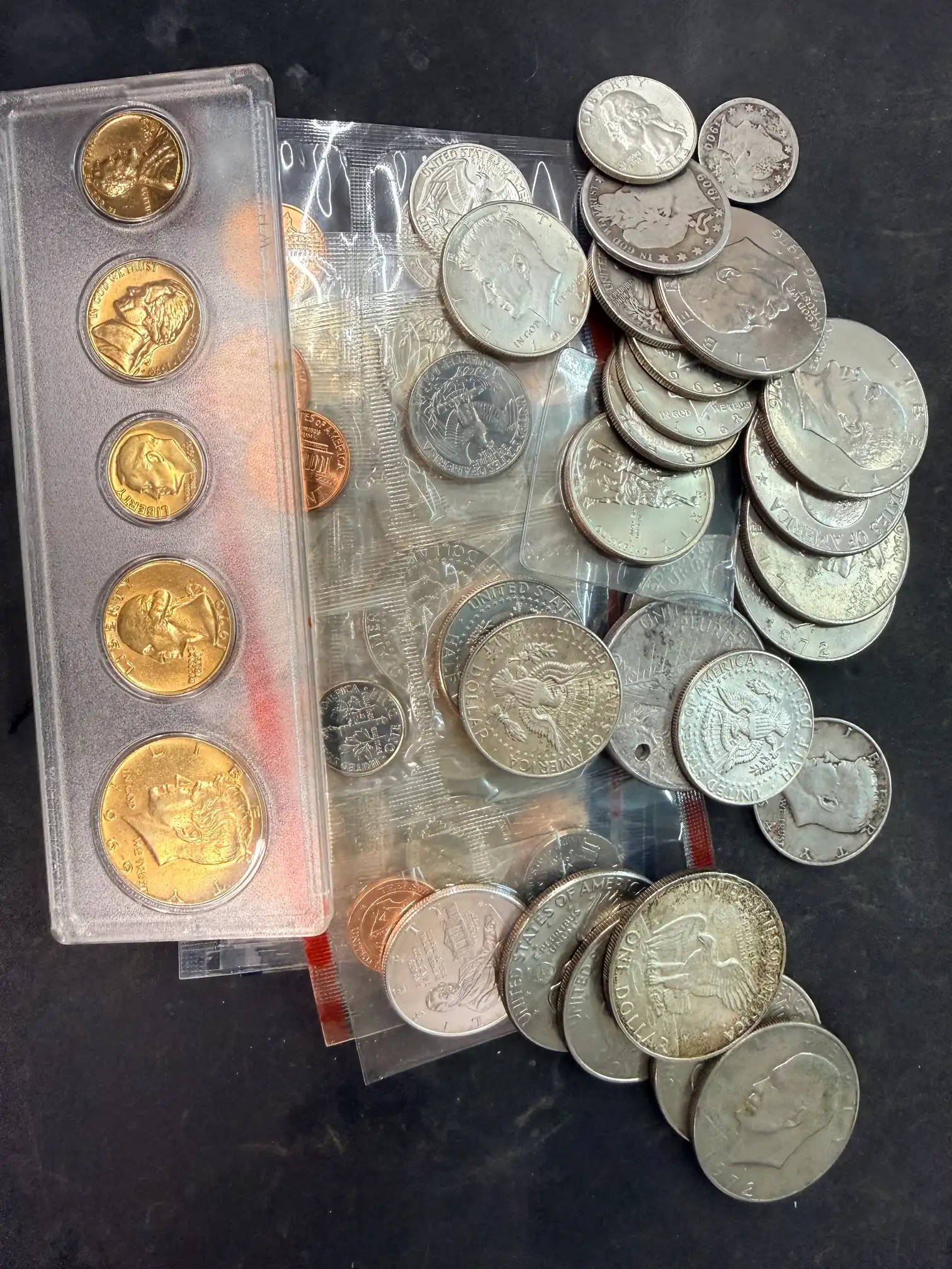 US mint sets, Kennedy and Eisenhower halves, and older silver coins spread on the counter